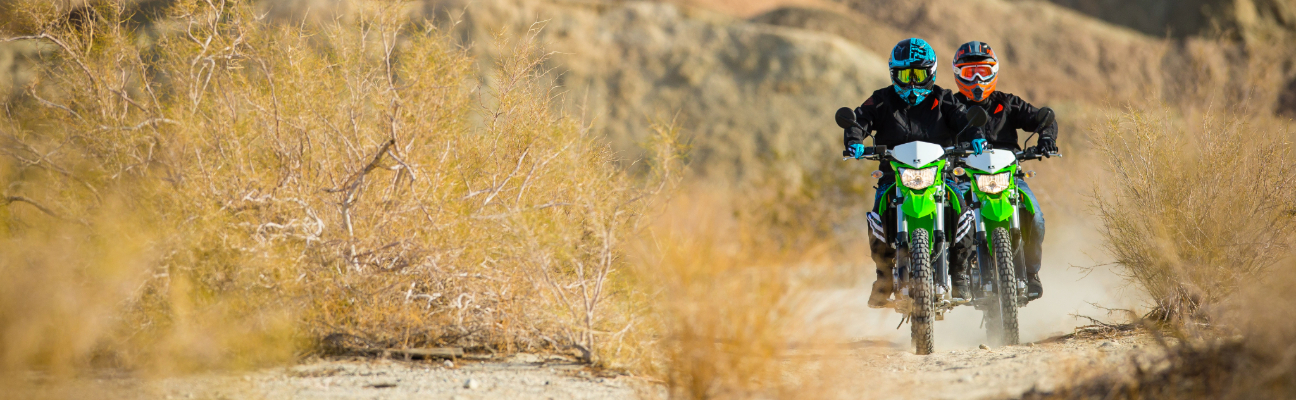 motorcyclists driving down dirt path